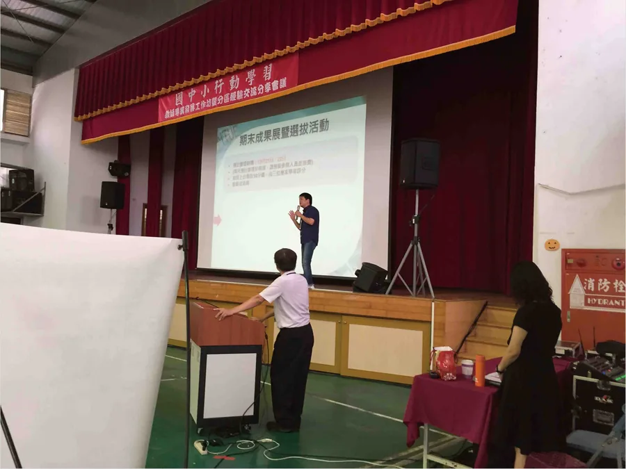 國中小行動學習分區經驗交流分享會議現場，講者於舞台簡報期末成果展選拔活動說明